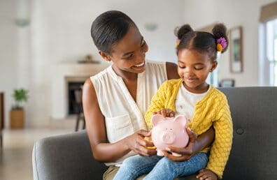 A mother showing her daughter a piggy bank.