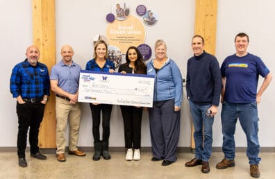 The winner of Husky Hack, Riddih Bajaj holding a large check alongside the judges of the competition.