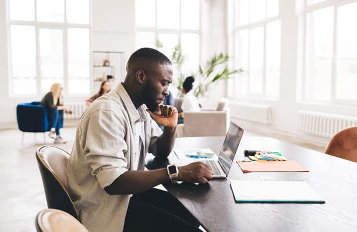 A concerned man working on a laptop.