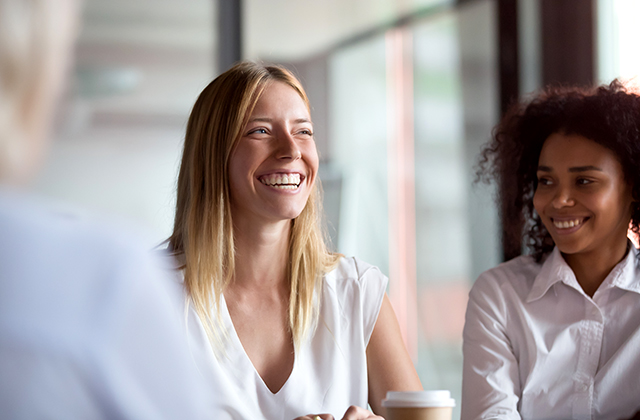 Happy young businesswoman coach mentor leader laughing at group meeting