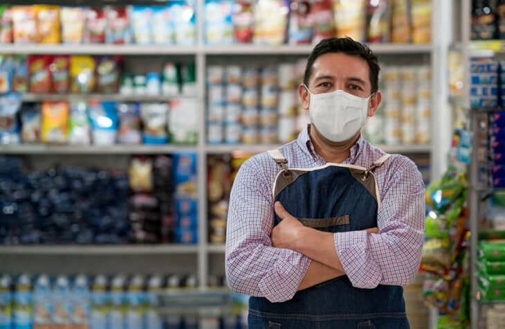 A shop owner wearing a mask.