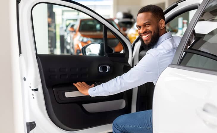 Car shopper sitting in a white sedan on showroom floor