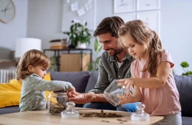 parent and young kids counting coins from savings jar