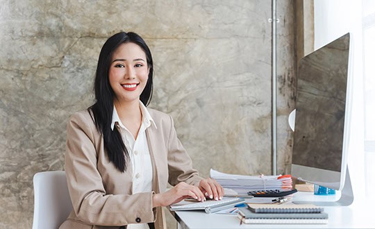 Smiling woman in office typing on computer