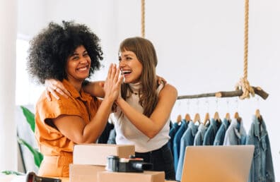 Cheerful store owners high-fiving each other.