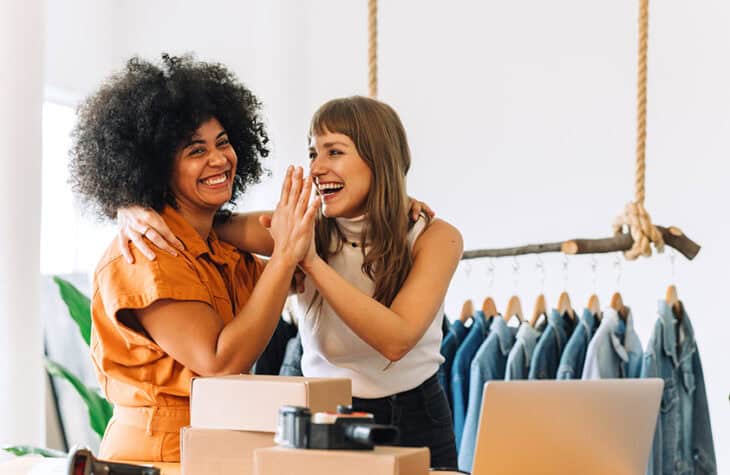 Cheerful store owners high-fiving each other.