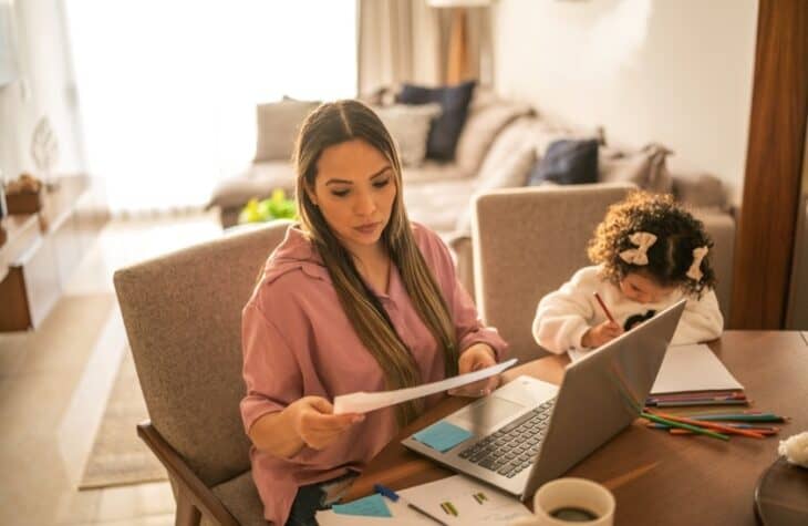 woman and child looking at paper in front of laptop at table