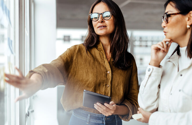 business colleagues discussing strategy on a smartboard