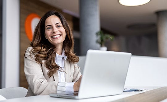 Smiling businesswoman working on laptop in modern office