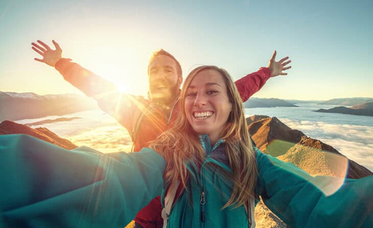 couple taking selfie on mountain top at sunrise
