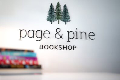 page & pine bookshop logo and stack of books on white counter.