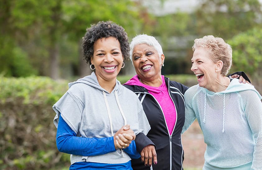 Three older women walking in the park laughing